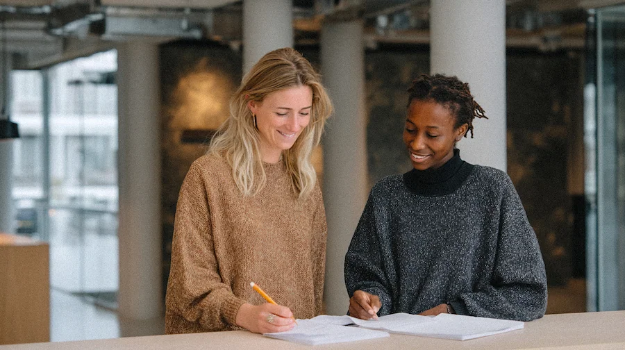 Två personer i härliga stickade tröjor tittar och skriver på papper.